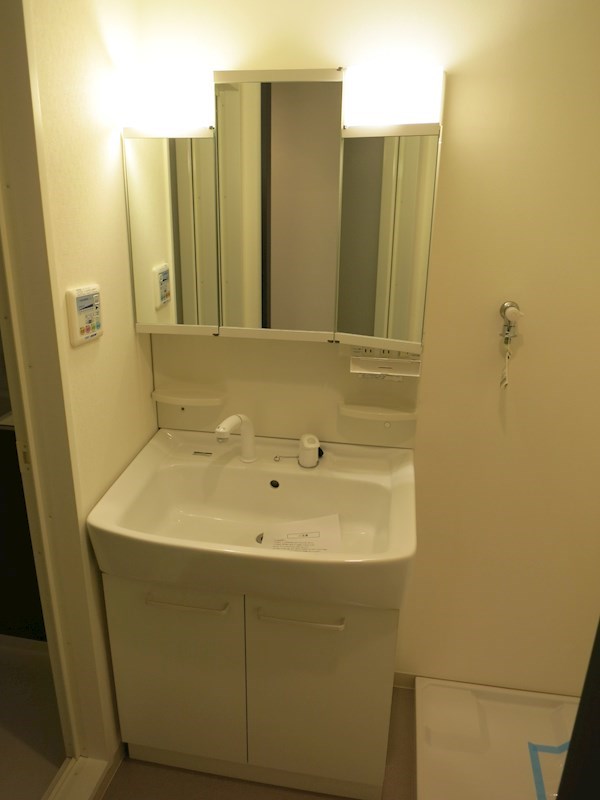 洗面台は三面鏡で収納力があります。壁には浴室乾燥機の操作パネル有り